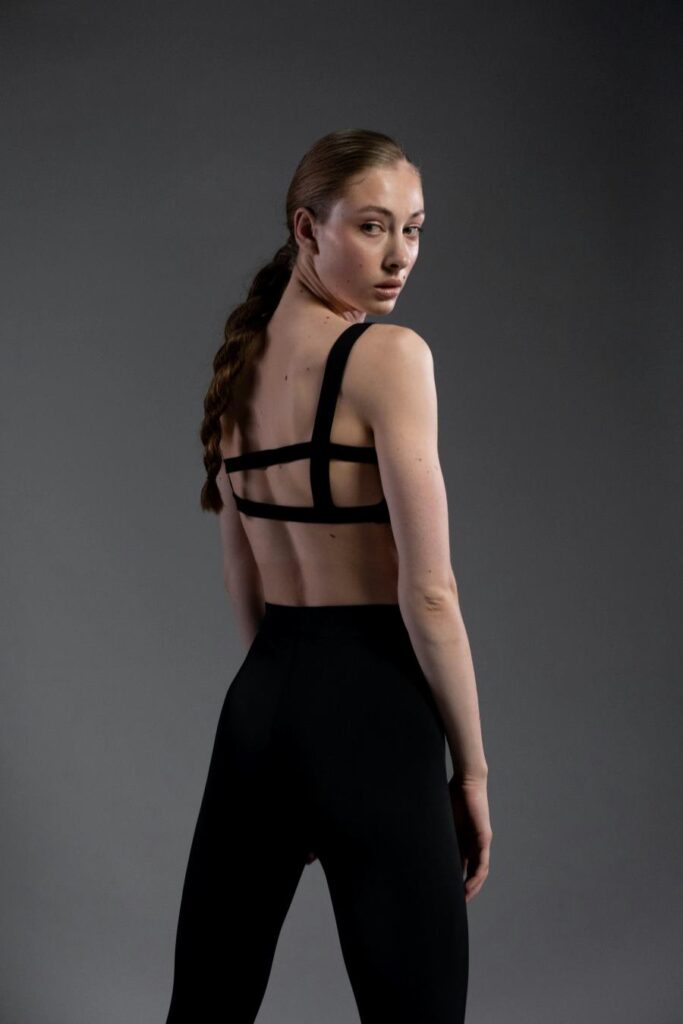 Woman standing in black set looking back at camera